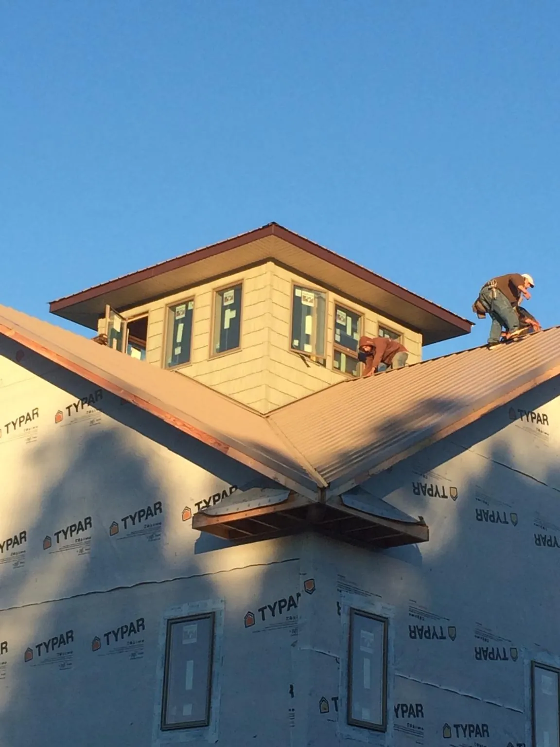 Roofers working around a rooftop cupola on a new metal roof at sunset — Roof Waterproofing in Carmel by Roofing Brothers